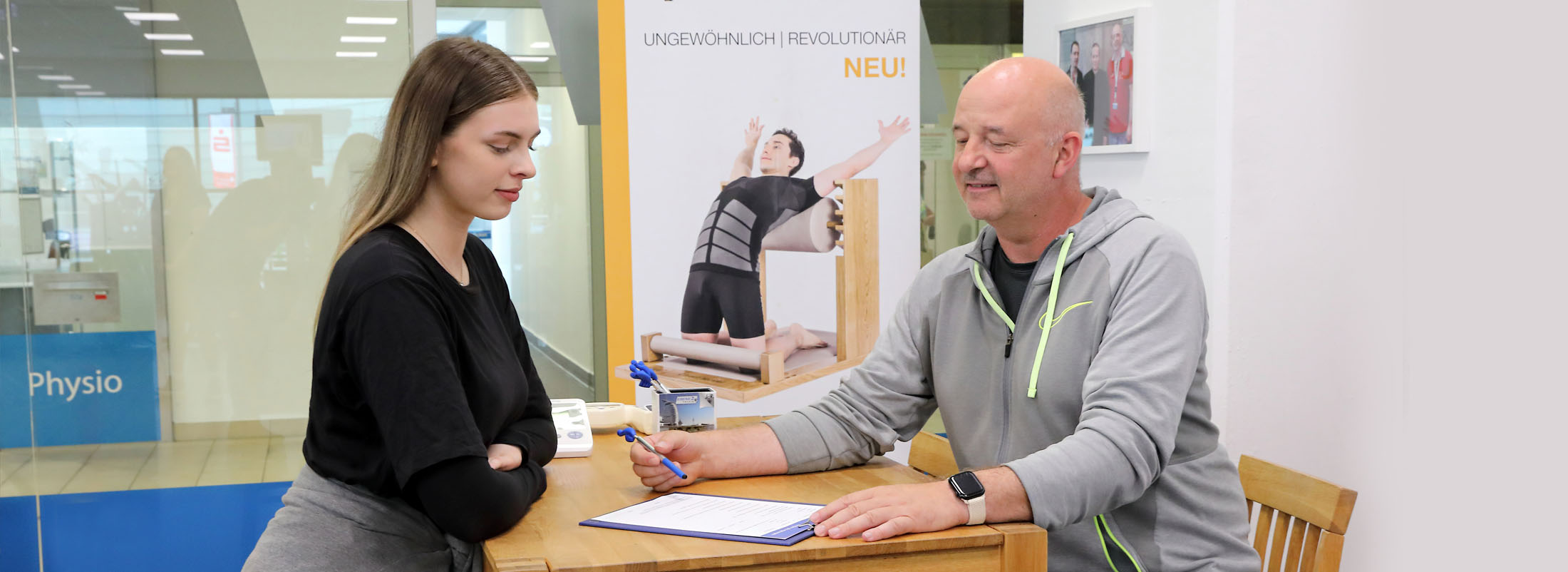 Ein Trainer legt der Frau gegenüber einen Vertrag zur Unterschrift vor.